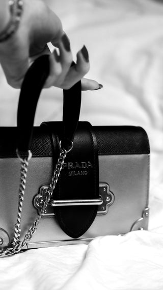 A woman holding the strap of a Prada bag
